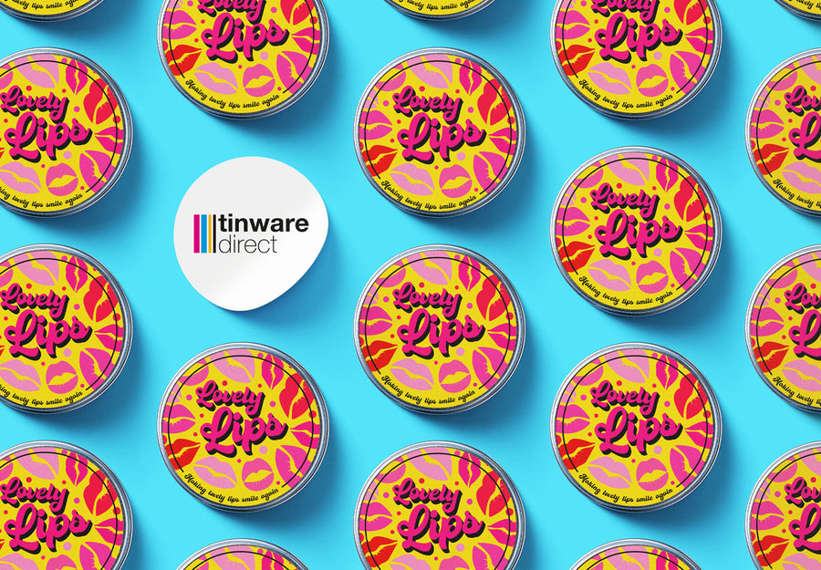 Lip balm tins with 'Lovely Lips' labels on in a production line with a blue background and the Tinware Direct logo on a label.