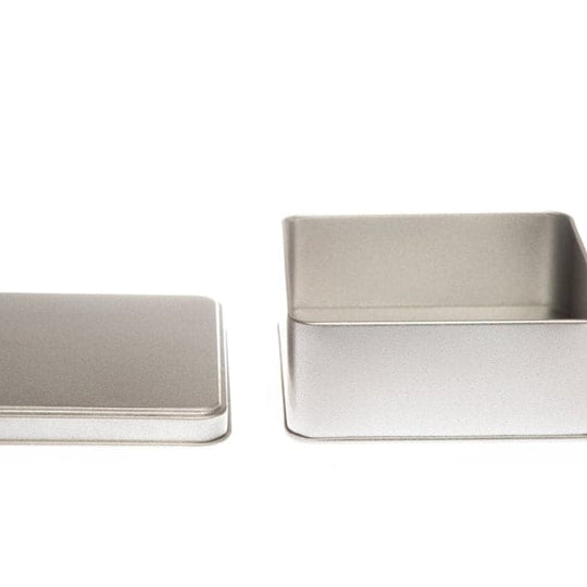 A square silver tin with its lid off to show the inside.