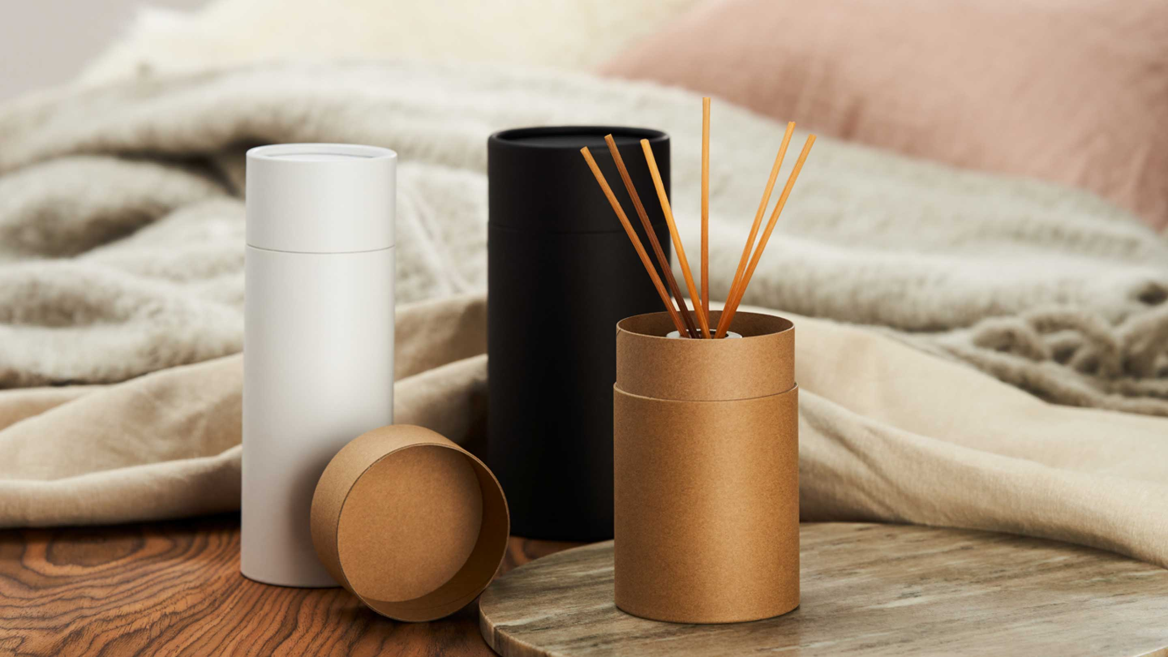 Three different coloured cardboard tubes in black, white and brown in a lounge with diffusers inside.