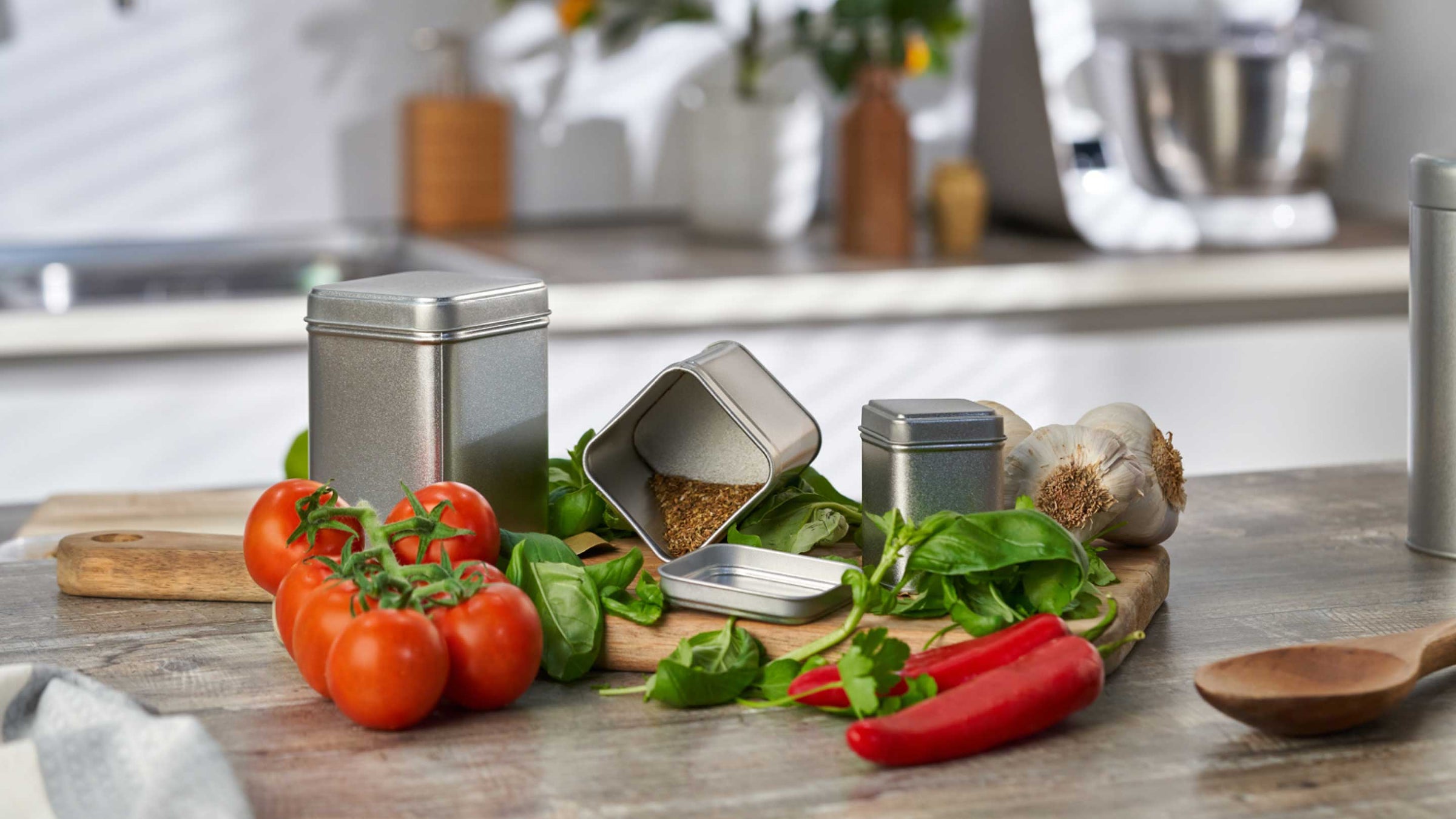 Metal tins with spices and herbs in surrounded by food.