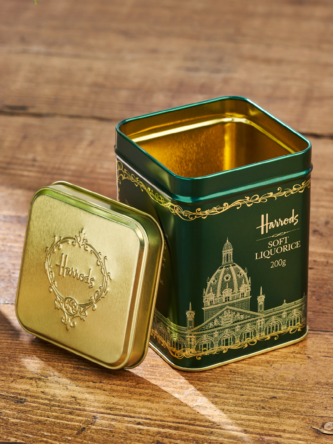 A green Harrods packaging tin for sweets. Gold is etched into the green design.
