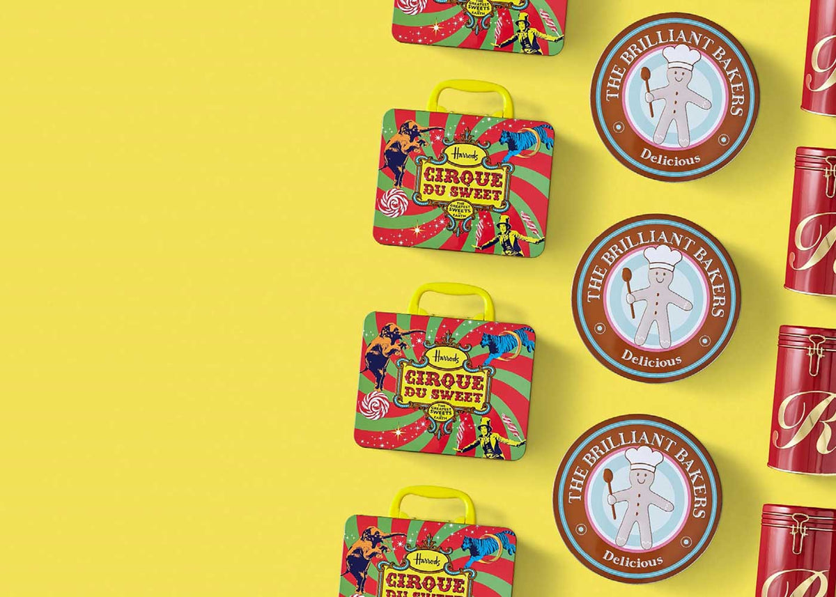 Three different types and shapes of tins laid out in a line against a yellow background. The metal packaging contains biscuits, cakes, sweets or coffee.