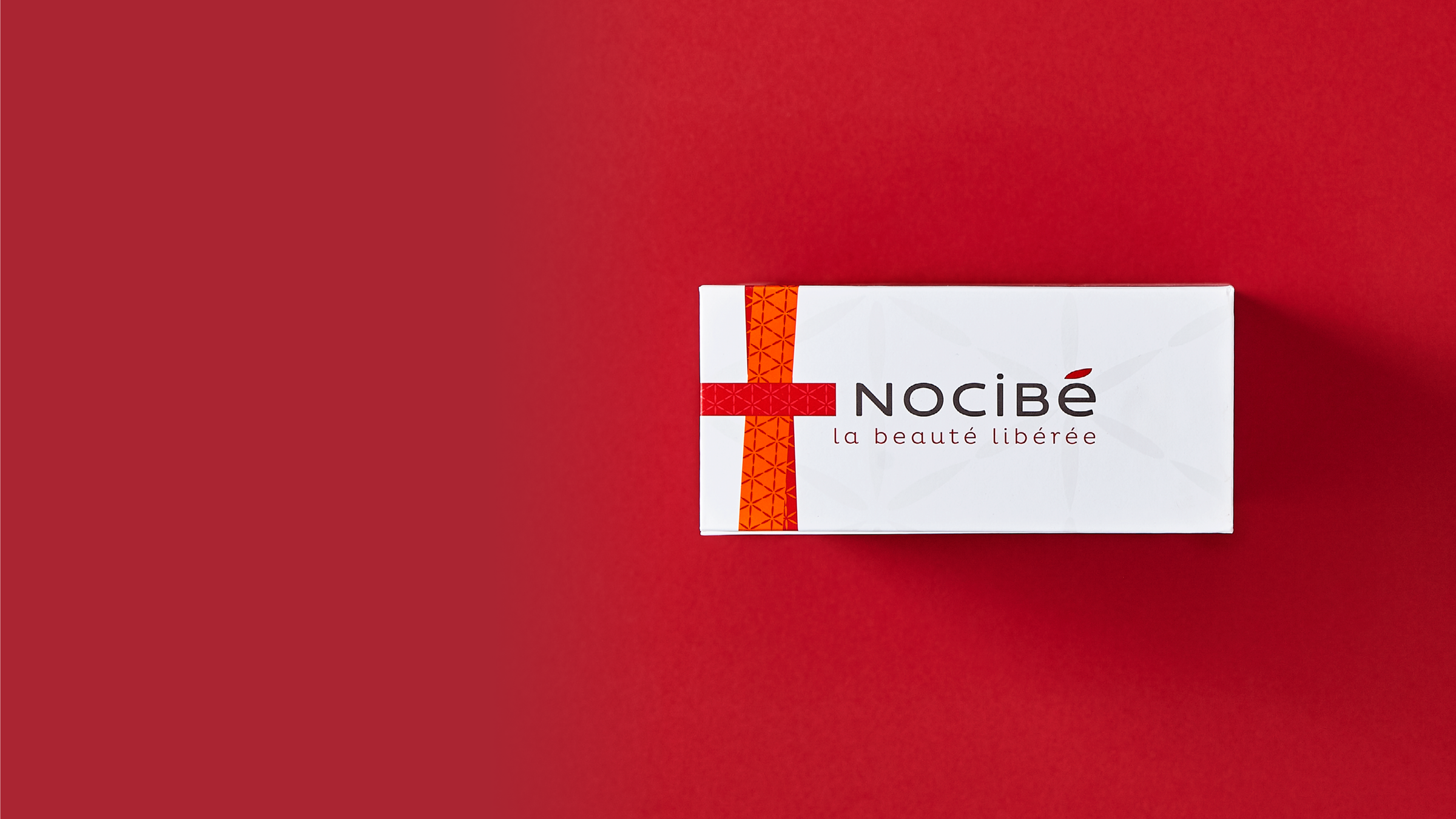 A white cardboard box with magnetic closure for Nocibe against a red background