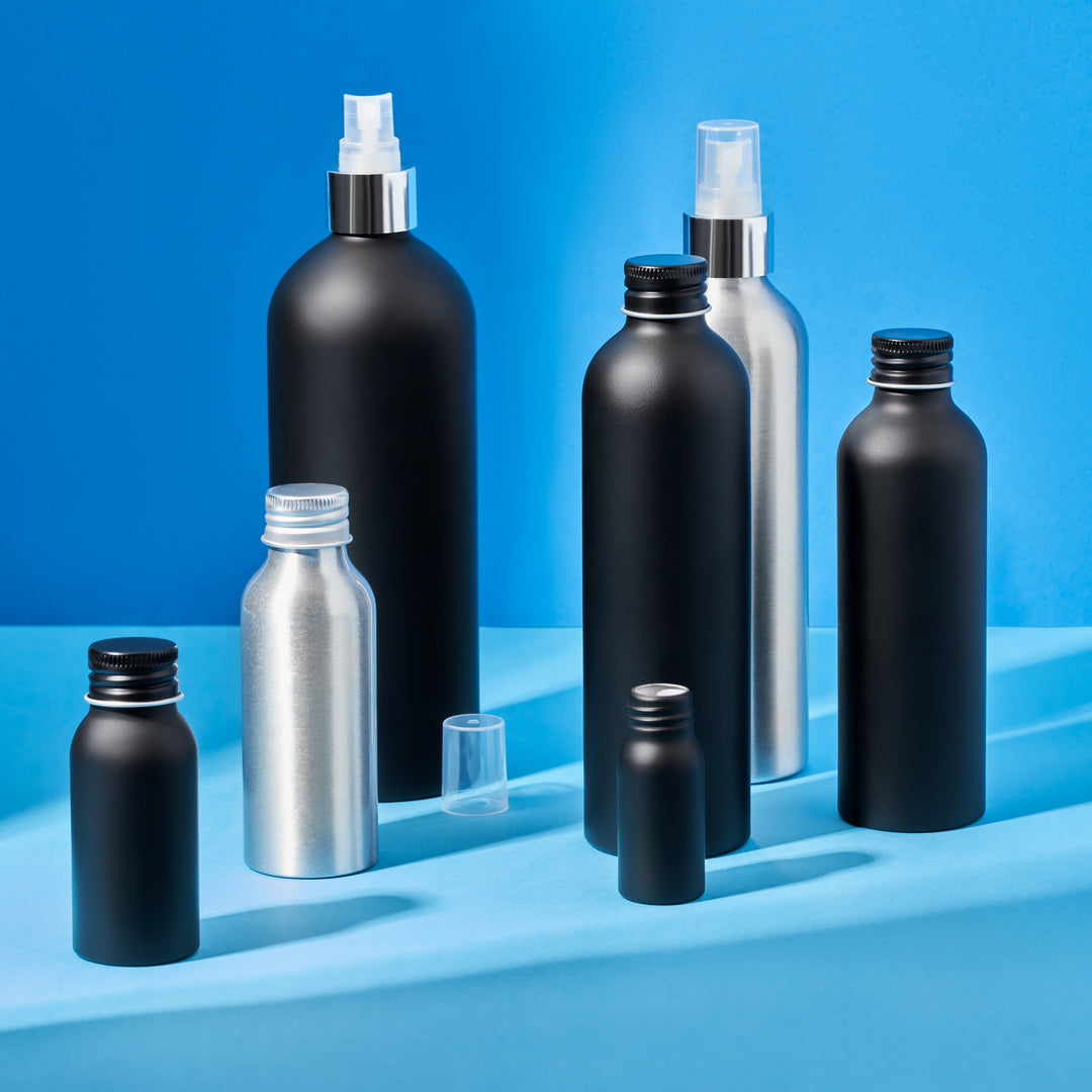 Collection of aluminium bottles with spray and pump caps on a blue background. 