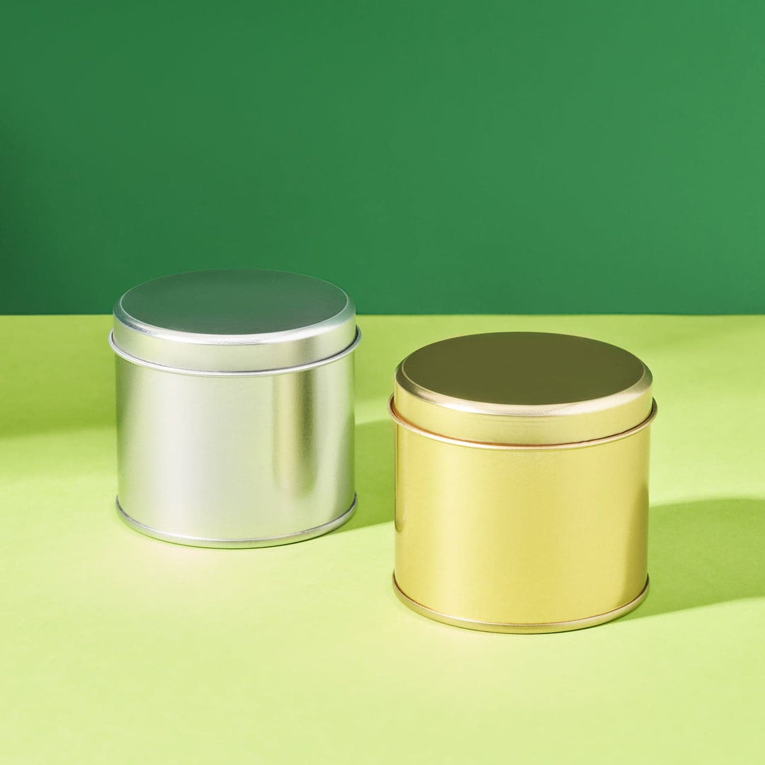 Slim welded side seam tins, one in gold, and one in silver. Packaging displayed on a green background. 