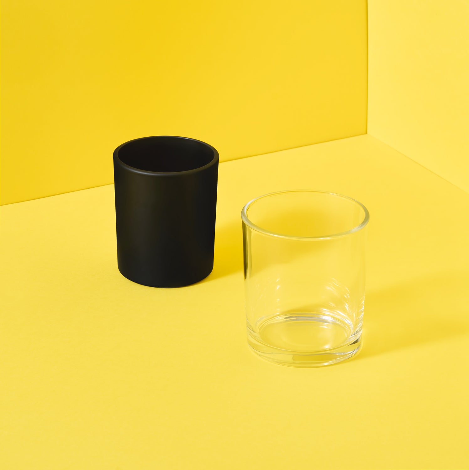 Glass candle jars on yellow background - black and clear