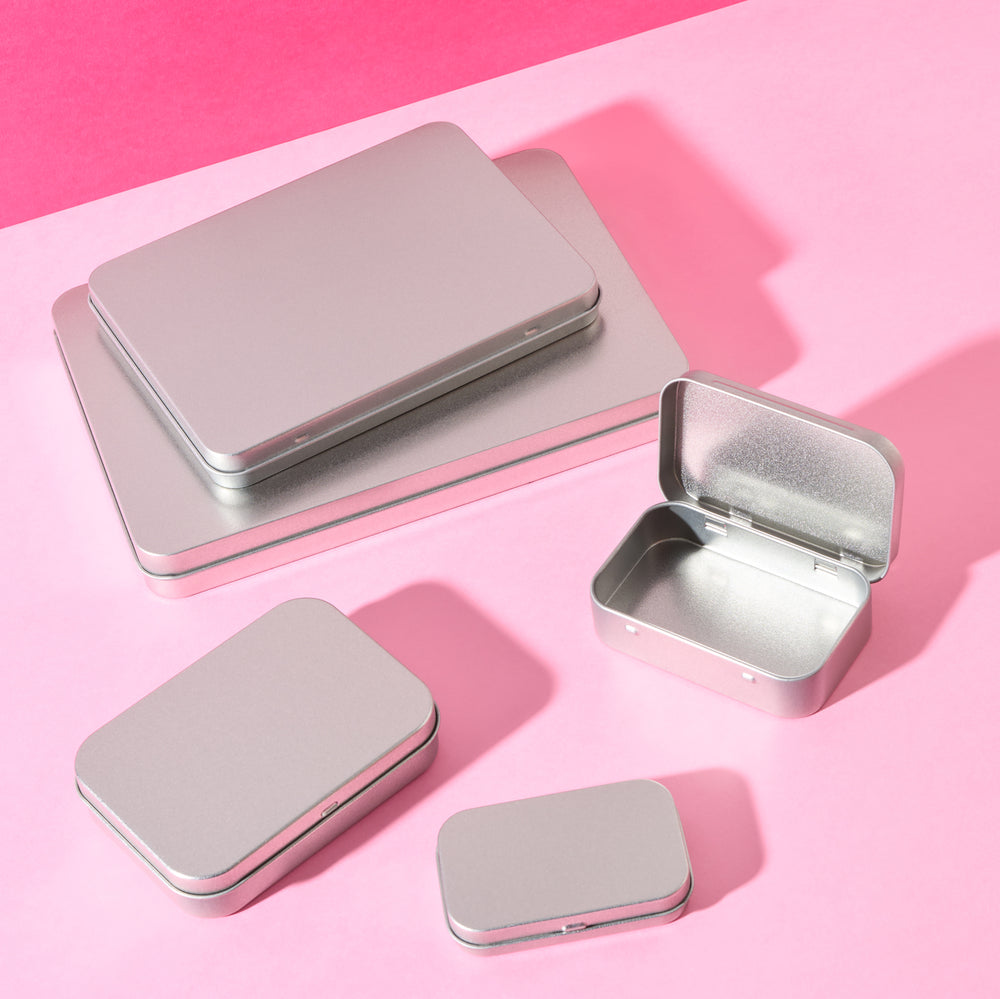 Flat tin packaging in various sizes on pink background.