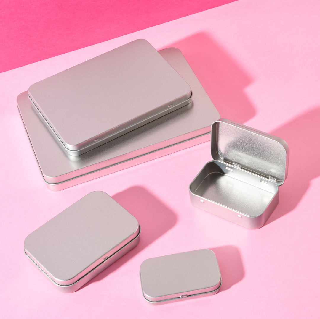 Flat tin packaging in various sizes on pink background.