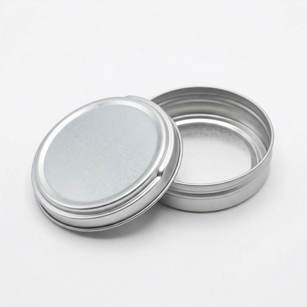 An open silver tin with push to open lid resting on the base.