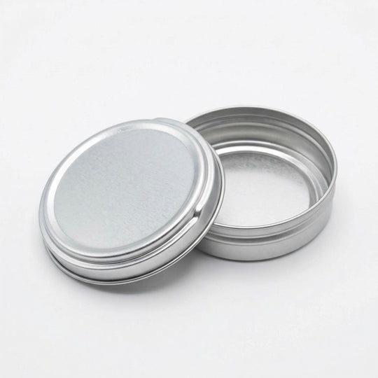 An open silver tin with push to open lid resting on the base.