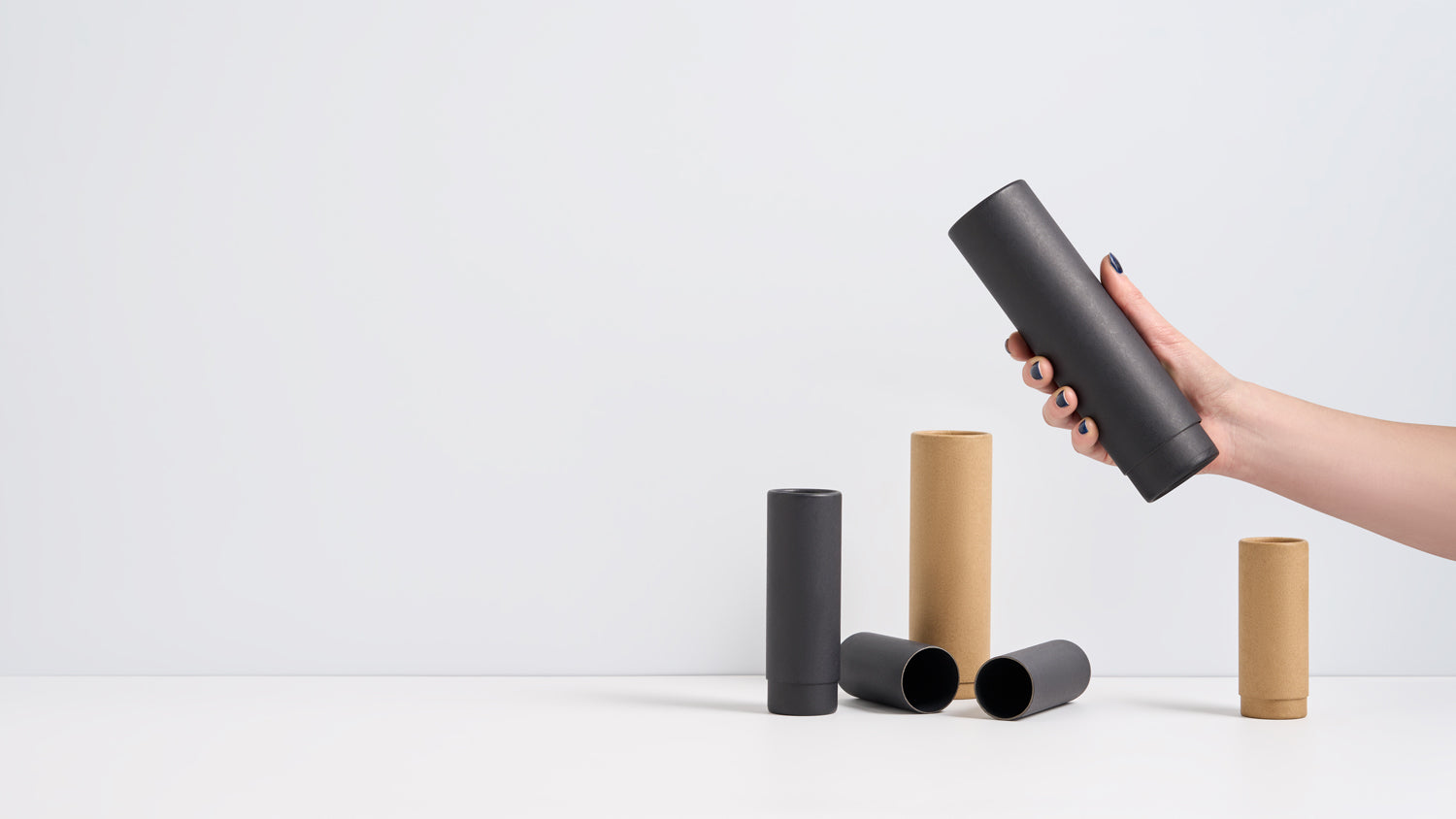 Hand holding a black telescopic packaging tube