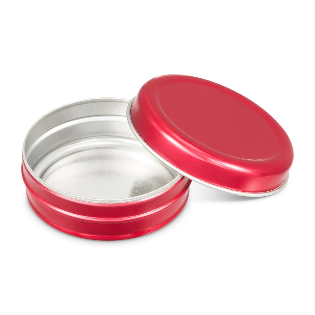 A red lip balm tin with the lid open showing the inside as silver.