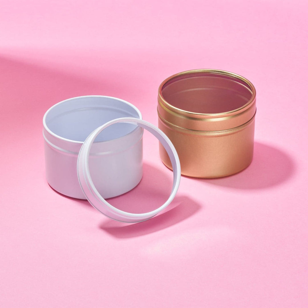 Two seamless tins with clear lids, one white and the other gold.