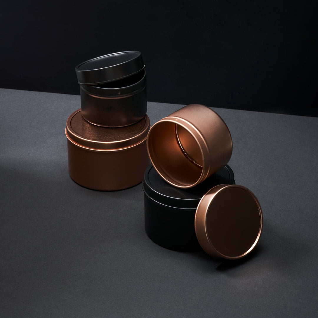 A collection of black and rose gold seamless tins in different sizes with lids.