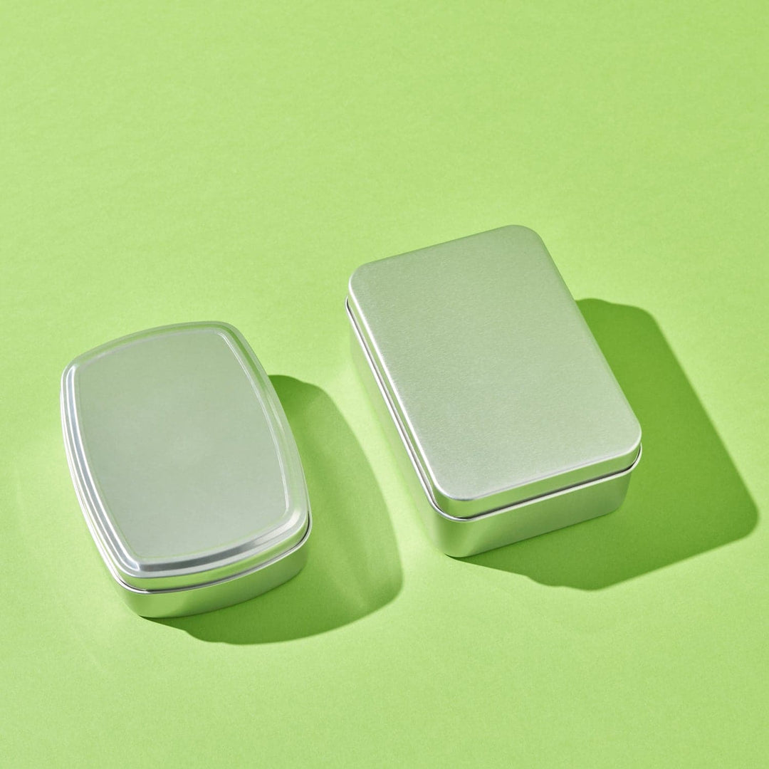 Two silver aluminium rectangular tins with slip lid. One tin features slightly curved sides.