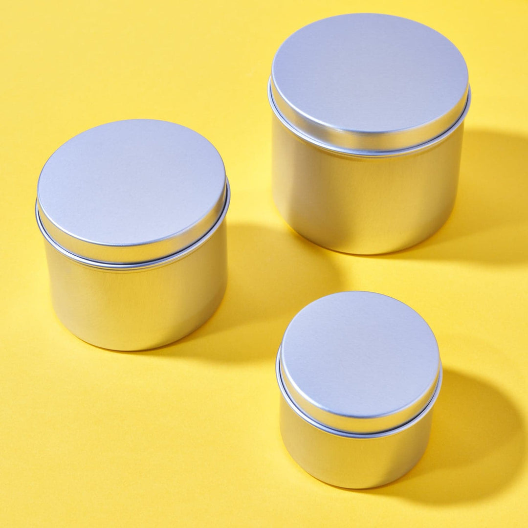 Set of three silver aluminum tins with lids against a yellow background
