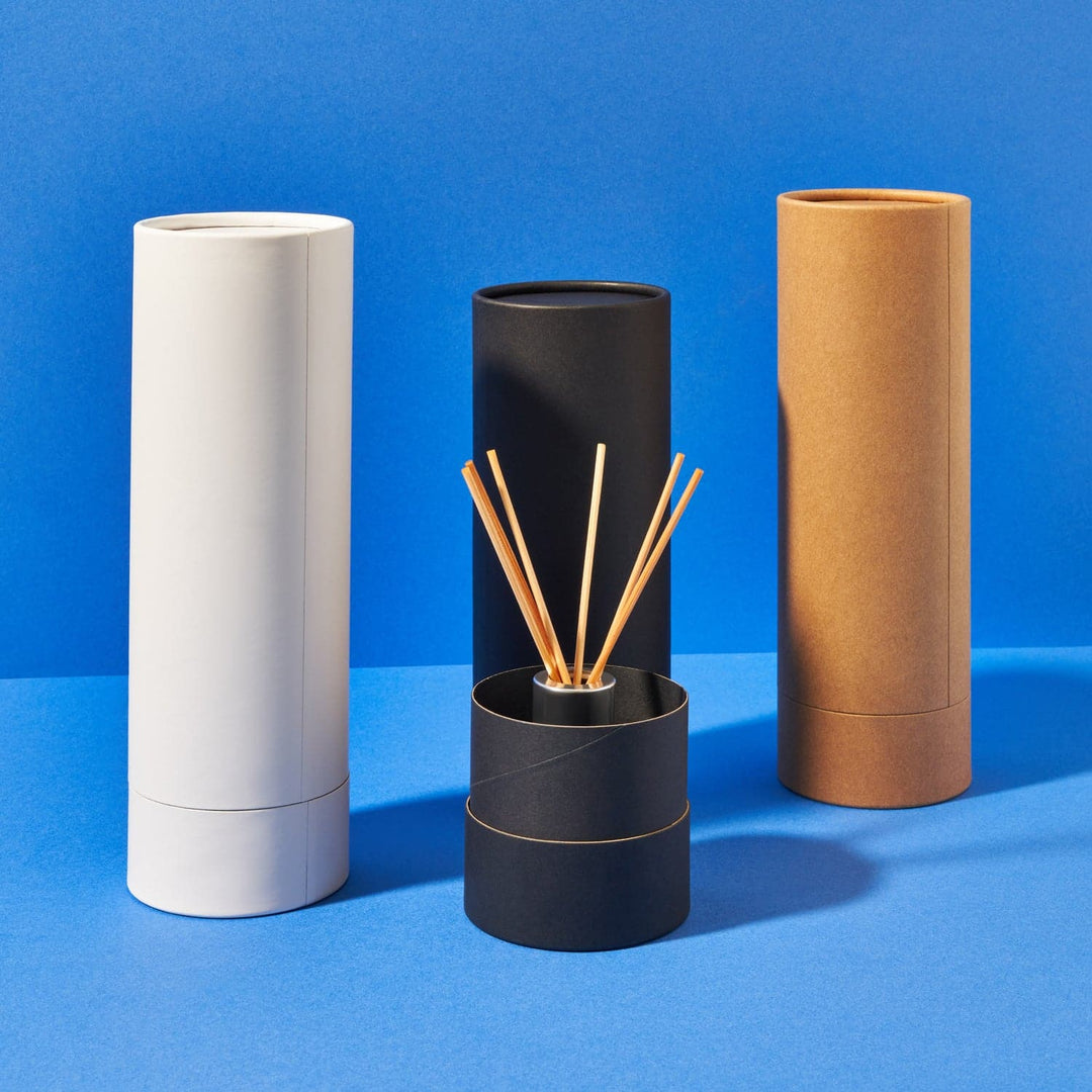 Collection image of cardboard tubes in black, white and brown. One is open and shows a reed diffuser inside.